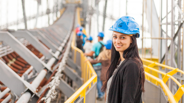 Construction worker wearing a blue hard hat poses on a catwalk on a construction site.